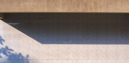 Sunlight and shadow of exposed aggregate finish cobblestone awning on surface white tile wall background in panoramic viewの写真素材