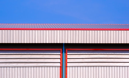 Aluminum Louvers and rain drain pipe on steel wall decoration with corrugated metal roof of industrial warehouse Building with blue clear sky backgroundの写真素材