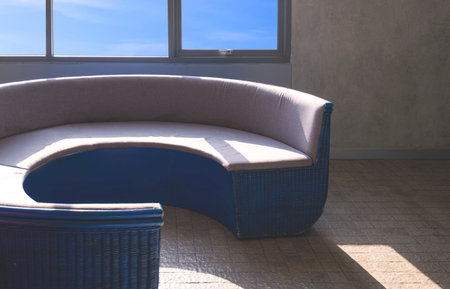 Sunlight and shadow on surface of empty curved couch near glass window on loft concrete wall in vintage living roomの写真素材