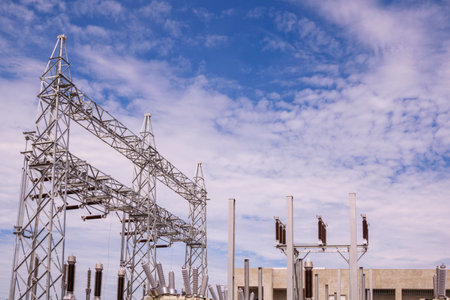 High voltage electric pylon structure and equipment with power distribution building substation under construction in construction site areaの写真素材
