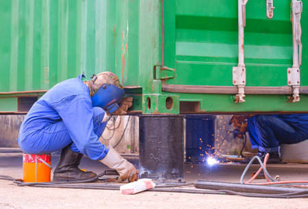 2 Welders welding metal bollards to use for support foundation of the old container that have been renovated to outdoor office or storage roomの写真素材