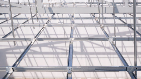 Aluminum c-line ceiling structure over white concrete wall inside of room in house construction site, high angle and perspective viewの写真素材