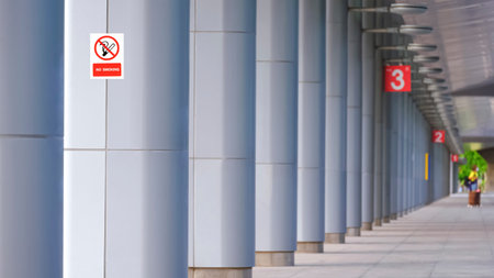 Focus at no smoking sign label on gray aluminium composite poles structure of covered walkway in front of train stationの写真素材
