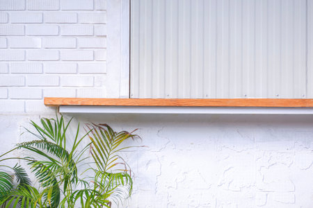 Minimal exterior Vintage Restaurant background. Wooden Counter and steel foldable awning on white Brick Wall with palm leaf in front of Coffee Shopの写真素材