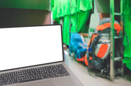 Close up of modern laptop with blurred background of backpacks on aisle inside of sleeper Train cabin at night, blank screen with clipping pathの写真素材