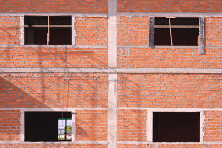 Background of brick wall structure and window frames of two storey house in construction siteの写真素材