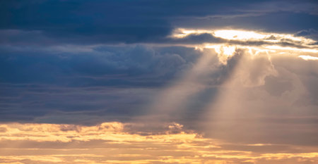 Sun rays shining through the overcast cloudy sky before rain in evening time, beautiful dramatic cloudscape sky backgroundの写真素材