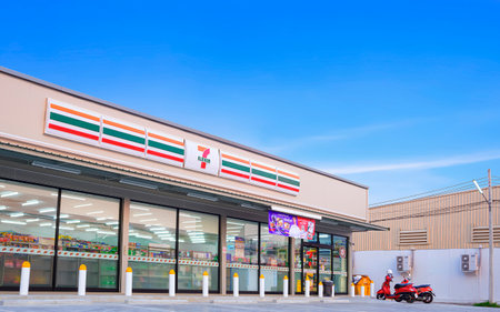 Samut Sakhon, Thailand - March 31, 2023 : Large 7-11 Convenience Building Store with customer service parking lot area against blue sky background, low angle and perspective side viewのeditorial素材
