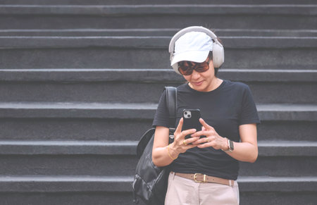 An Asian female tourist in casual clothing style taking selfie or video with mobile phone in outdoors attraction area while creating travel content on social mediaの写真素材