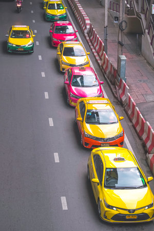 Bangkok, Thailand - October 13,2023 : Row of metered taxis lined up on city street in long line while waiting to pick up passengers in vertical frameのeditorial素材