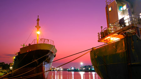 The old oil tanker ships moored in shipyard area at harbor during maintenance work against colorful twilight sky backgroundの写真素材