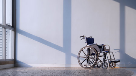 Empty Wheelchair on cobblestone tile floor with sunlight and shadow on gray interior wall surfaceの写真素材