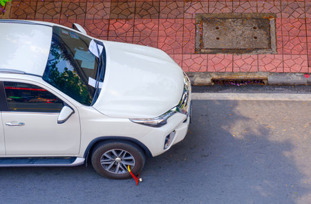 Bangkok, Thailand - April 12,2021: White car on roadside had been wheel locked because of illegal parking in prohibited parking space zone with traffic violation ticket on windshieのeditorial素材
