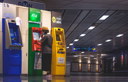 Bangkok, Thailand - January 01,2024 : A female tourist is making financial transaction on ATM banks machine in the corridor inside of subway stationのeditorial素材