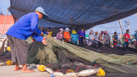 Samut Sakhon, Thailand - March 31, 2023: Asian Fisherman and  workers group repairing broken nets on an outdoor patioのeditorial素材