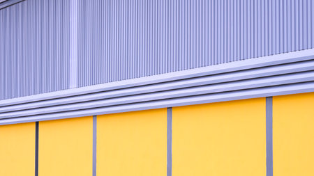 Industrial factory building with steel louver ventilation on gray aluminum corrugated iron and yellow concrete wall, perspective side viewの写真素材