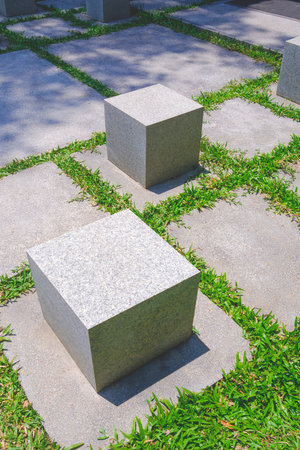 Gray Cubic Marble Seats on Granite Stone Tile Pavement Floor with Green Grass in Rest Area at Public...