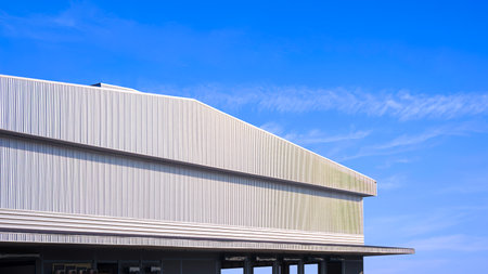 Large Factory Building, Architecture Industrial Warehouse with Corrugated Metal Awning and Gable Roof against Blue Sky Background, Low angle and Perspective Side Viewの写真素材