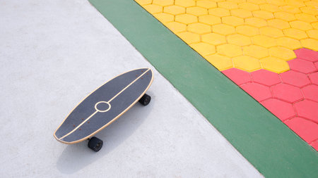 Skateboard on concrete yard floor with colorful hexagon cobblestone pavement decoration in outdoor...