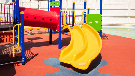 Slide with playground equipment on colorful rubber floor in kindergarten school
