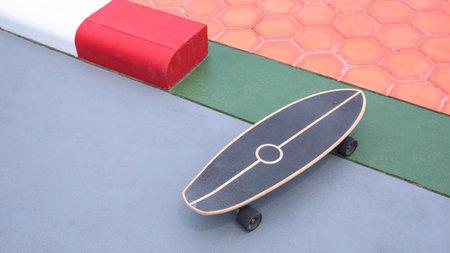 Skateboard on colorful concrete yard floor with hexagon cobblestone pavement decoration in outdoor areaの写真素材