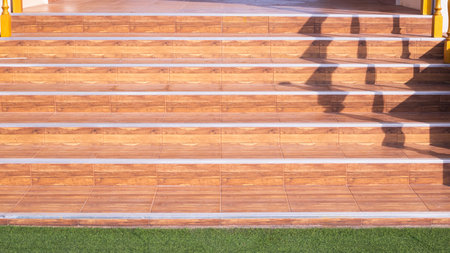 Tile stair steps with wood pattern and green turf in entrance way of vintage house building, front...