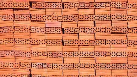 New perforated brick construction material stacked background, Pile of red bricks backdrop