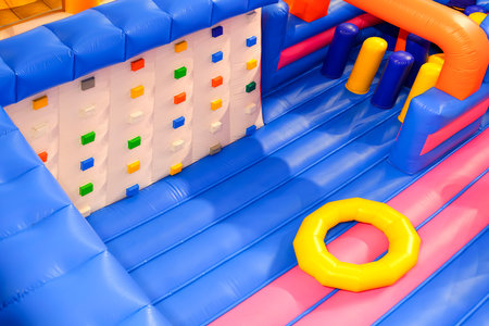 Inflatable jumping castle with colorful playground climbing equipment inside of shopping mall, high...
