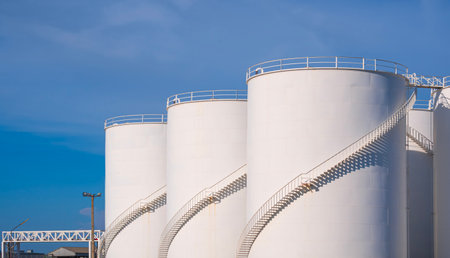 White storage fuel tanks group with oil pipeline system in petrol industry area at harbor against...