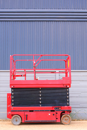 Electric scaffolding near precast concrete fence wall outside of warehouse factory building...