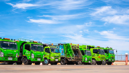 Samut Sakhon, Thailand - August 04, 2025 : Row of many green garbage trucks parked in parking lot of...