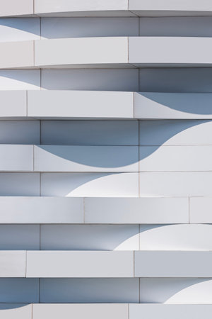 White and gray 3d dimension curve lines of aluminium composite tile wall of modern exterior building decoration, Abstract geometric architecture vertical background in minimal designの写真素材
