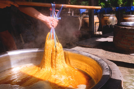Artisans' hands dyeing silk threads with natural ingredients inside of workshop. Close up and...