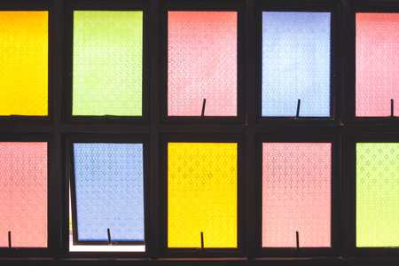 Colorful stained glass window panels with geometric patterns in yellow, green, red, and blue tones....