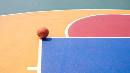 Minimalist basketball on colorful outdoor court with vibrant geometric pattern, high angle view with...