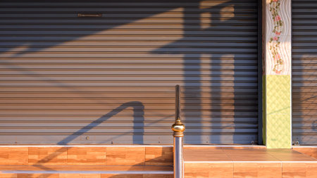 Roller shutter door with railing shadow in golden morning light. Minimalist urban background in...