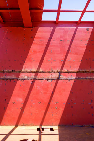 Red industrial metal wall with welded seams and strong geometric shadows. Minimal architecture...