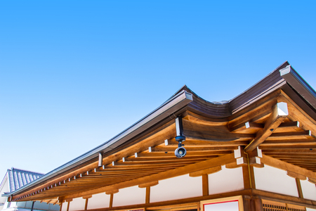 KYOTO, JAPAN - MARCH 12, 2018: Security system CCTV and details of traditional wooden Japanese temple roof inside the Fushimi Inari Shrine is the famous Shinto shrine in Kyoto, Japan.のeditorial素材
