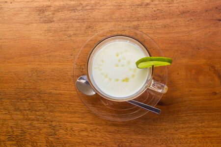 Lemon yogurt fresh milk in a clear glass placed on a brown wooden table with sea water surface background. Top view.の写真素材
