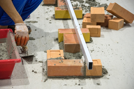 Bricklayer installing bricks, Bricklayer worker installing brick masonry on exterior wall with trowel putty knifeの写真素材