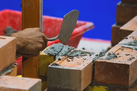 Bricklayer installing bricks, Bricklayer worker installing brick masonry on exterior wall with trowel putty knifeの写真素材
