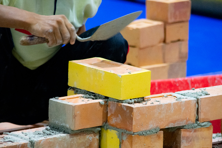 Bricklayer installing bricks, Bricklayer worker installing brick masonry on exterior wall with trowel putty knifeの写真素材