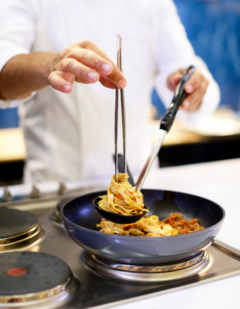 Chef cooking pasta, Chef serves spaghetti carbonara on the plate in the kitchenの写真素材