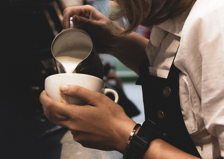 Barista pouring milk in to coffee, Barista making coffee with latte artの写真素材