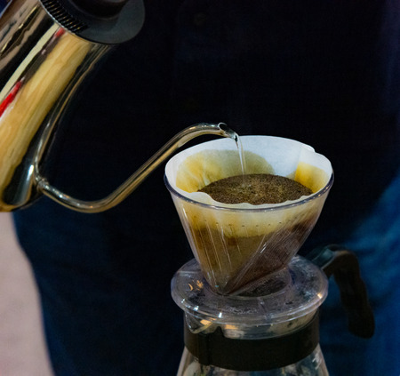 Drip coffee brewing, Barista pouring water on coffee ground with filterの写真素材