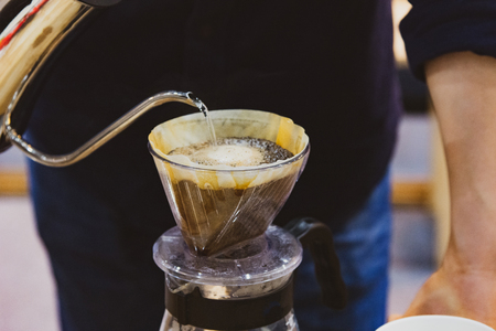 Drip coffee brewing, Barista pouring water on coffee ground with filterの写真素材
