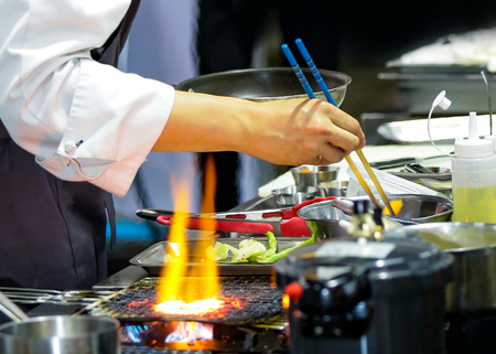 Chef cooking with flame in a frying pan on a kitchen stove, Chef in restaurant kitchen at stove with panの写真素材