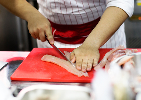 cut fish fillet in a fish shop, chef cutting fish in the kitchenの写真素材