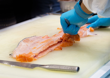 chef slicing raw fresh salmon, Chef preparing a fresh salmon on a cutting board