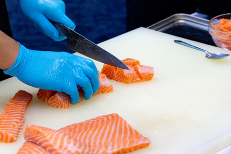chef slicing raw fresh salmon, Chef preparing a fresh salmon on a cutting boardの写真素材